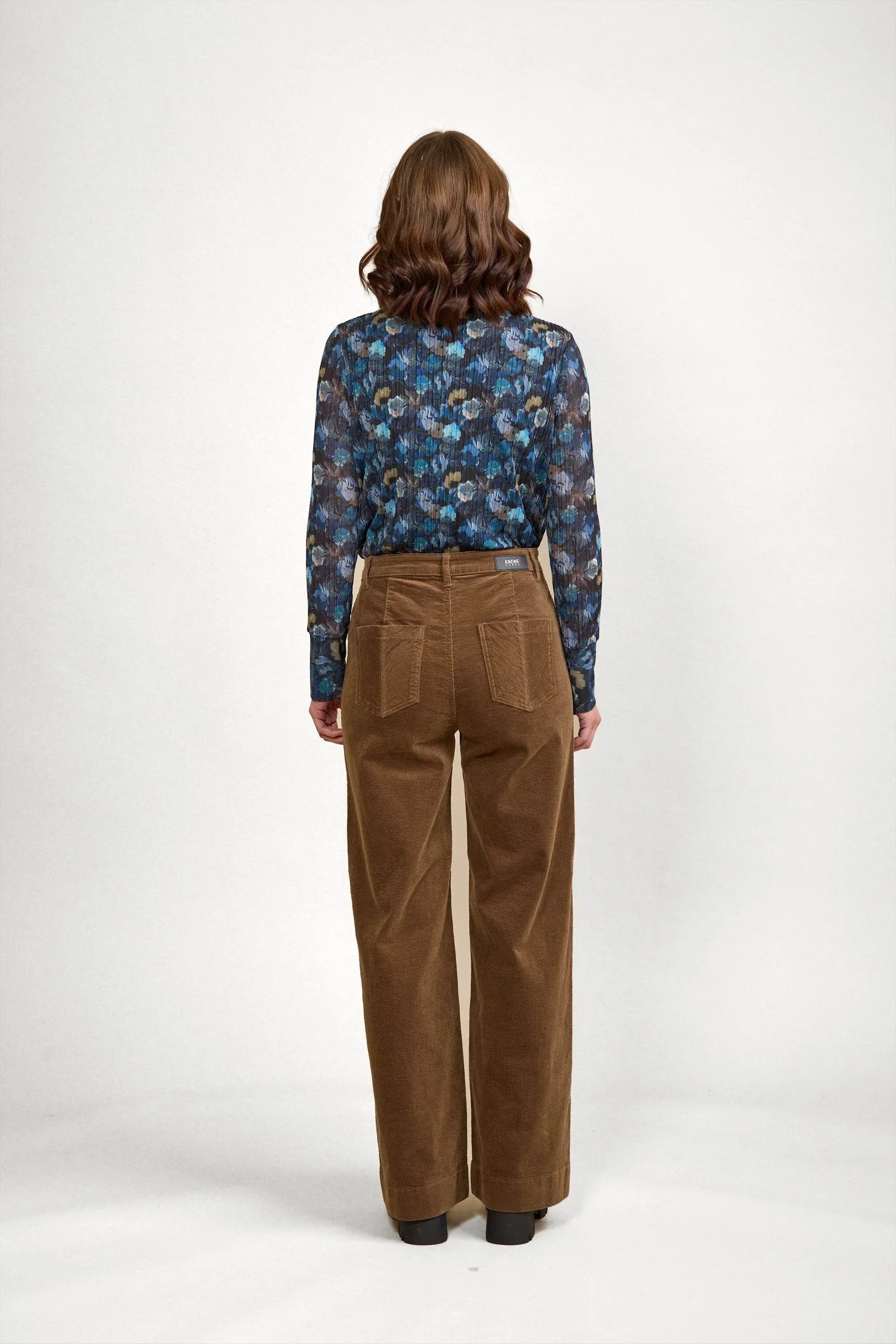 Brown corduroy wide-leg pants with back pockets, paired with floral long-sleeve top