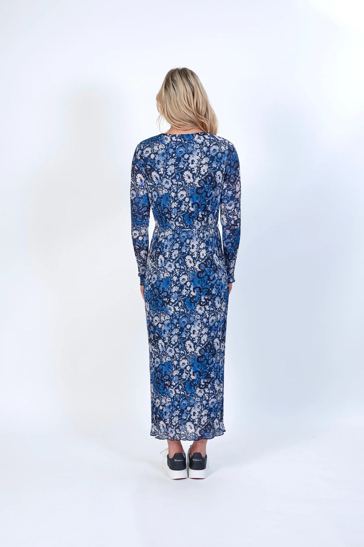 Woman wearing long-sleeve blue floral maxi dress with sneakers, back view