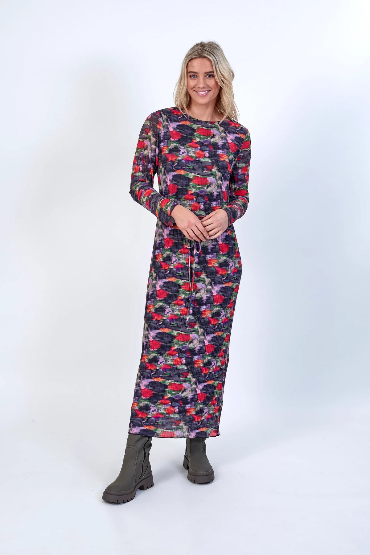 Woman wearing a long sleeve floral maxi dress with abstract red, purple, and green patterns
