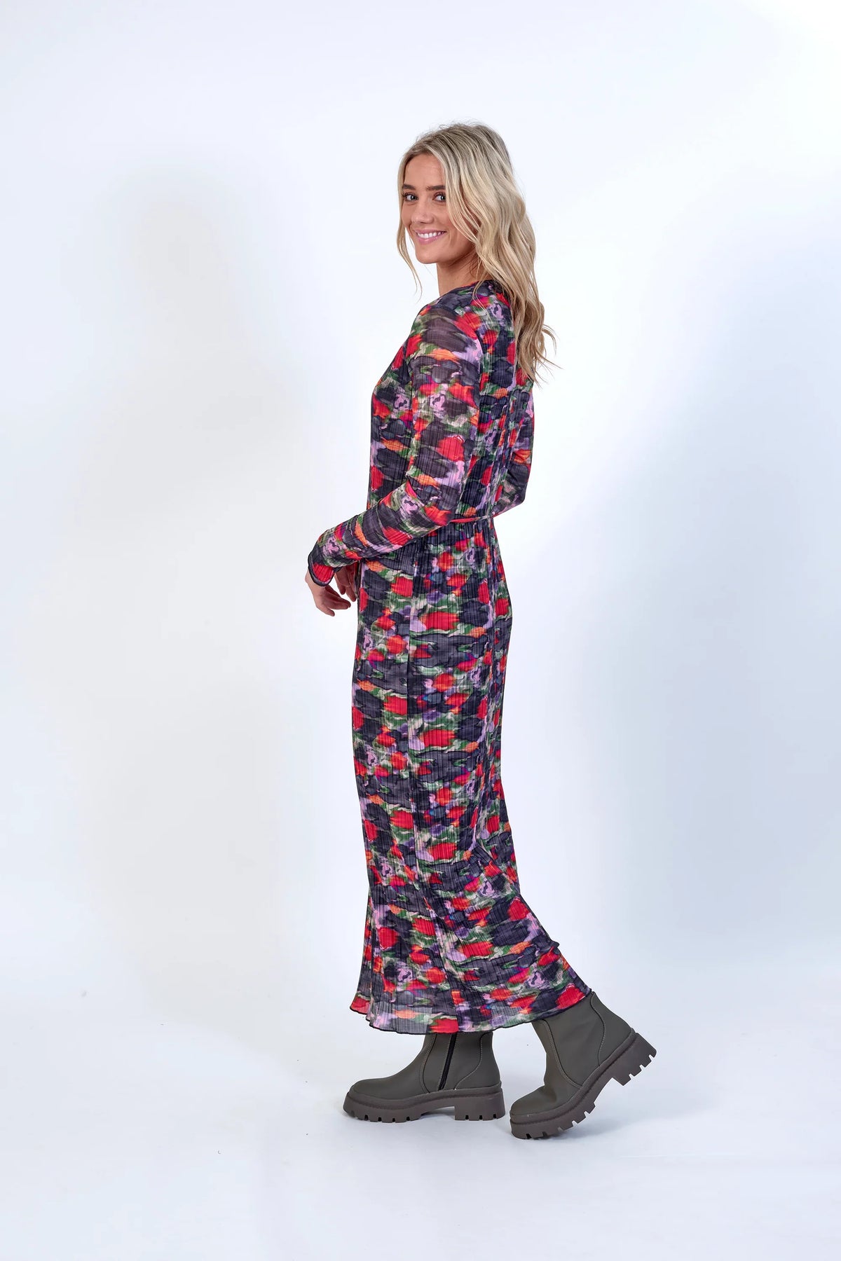 Woman wearing a long sleeve floral print dress and chunky ankle boots, side view