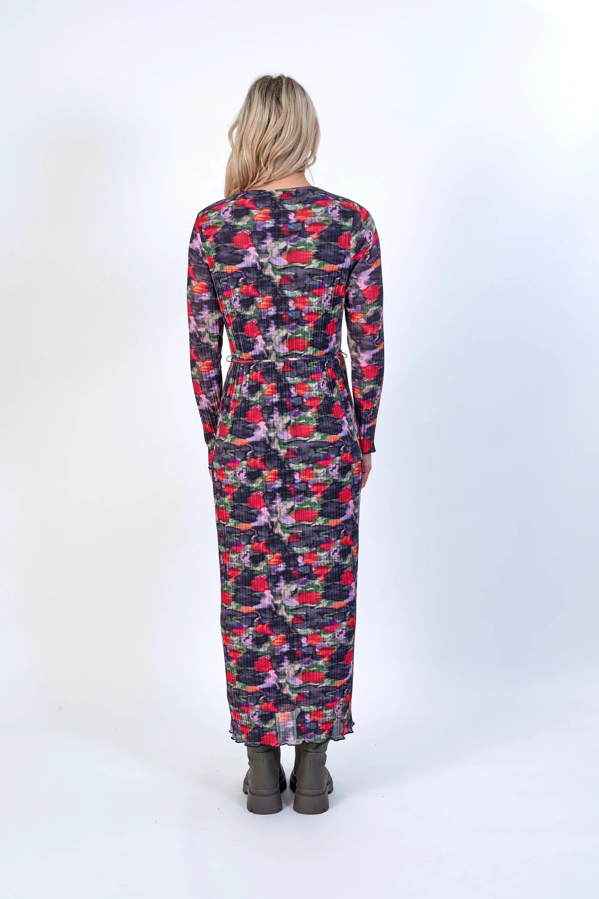 Woman wearing long sleeve floral print knit dress, back view, in studio setting