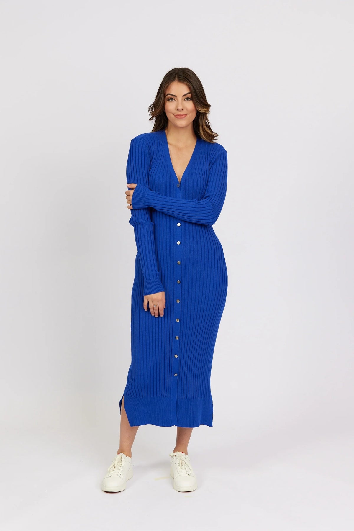 Woman wearing a ribbed electric blue button-down knit dress with long sleeves and white sneakers