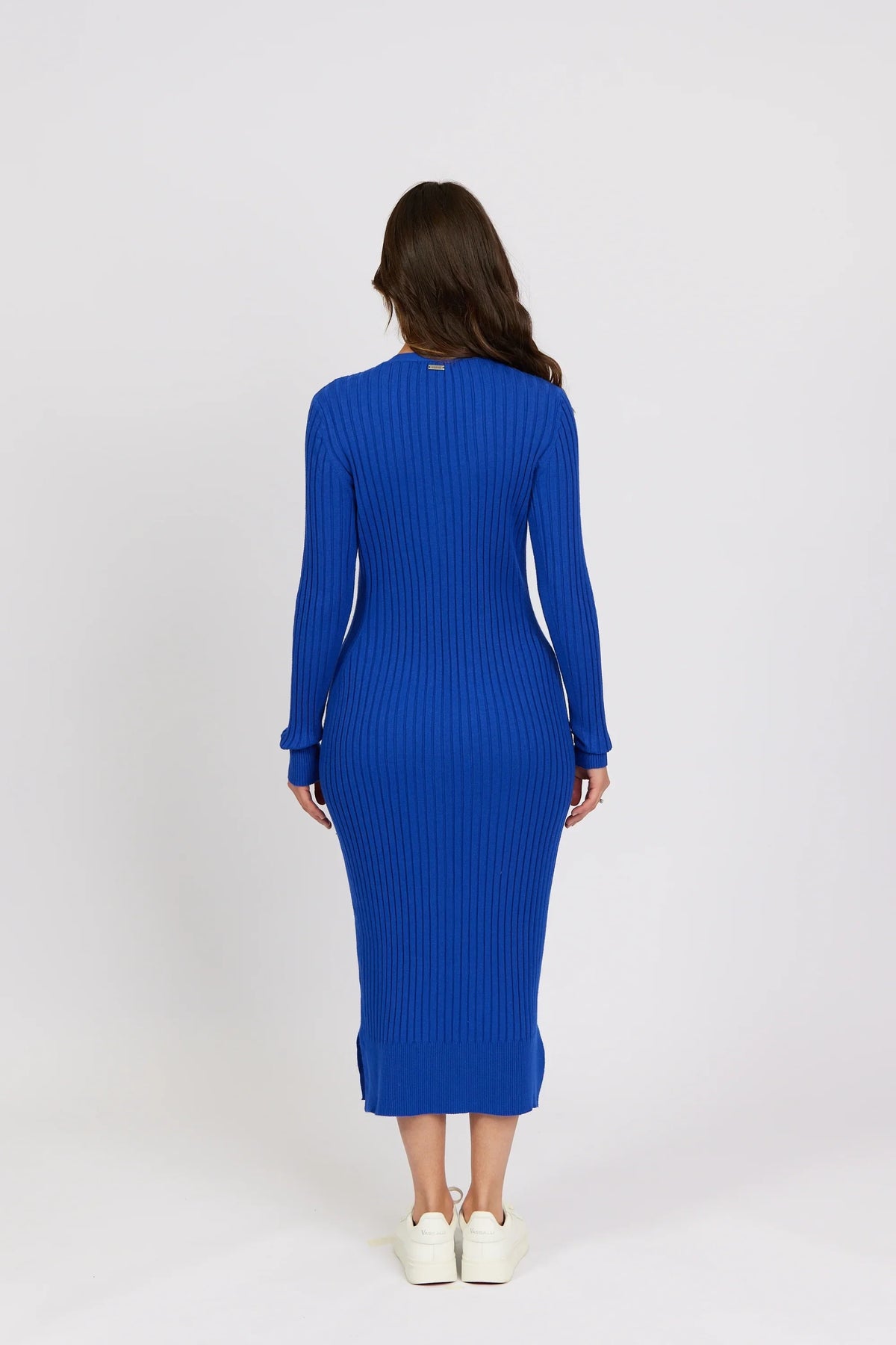 Woman wearing a ribbed electric blue knit midi dress with long sleeves, back view