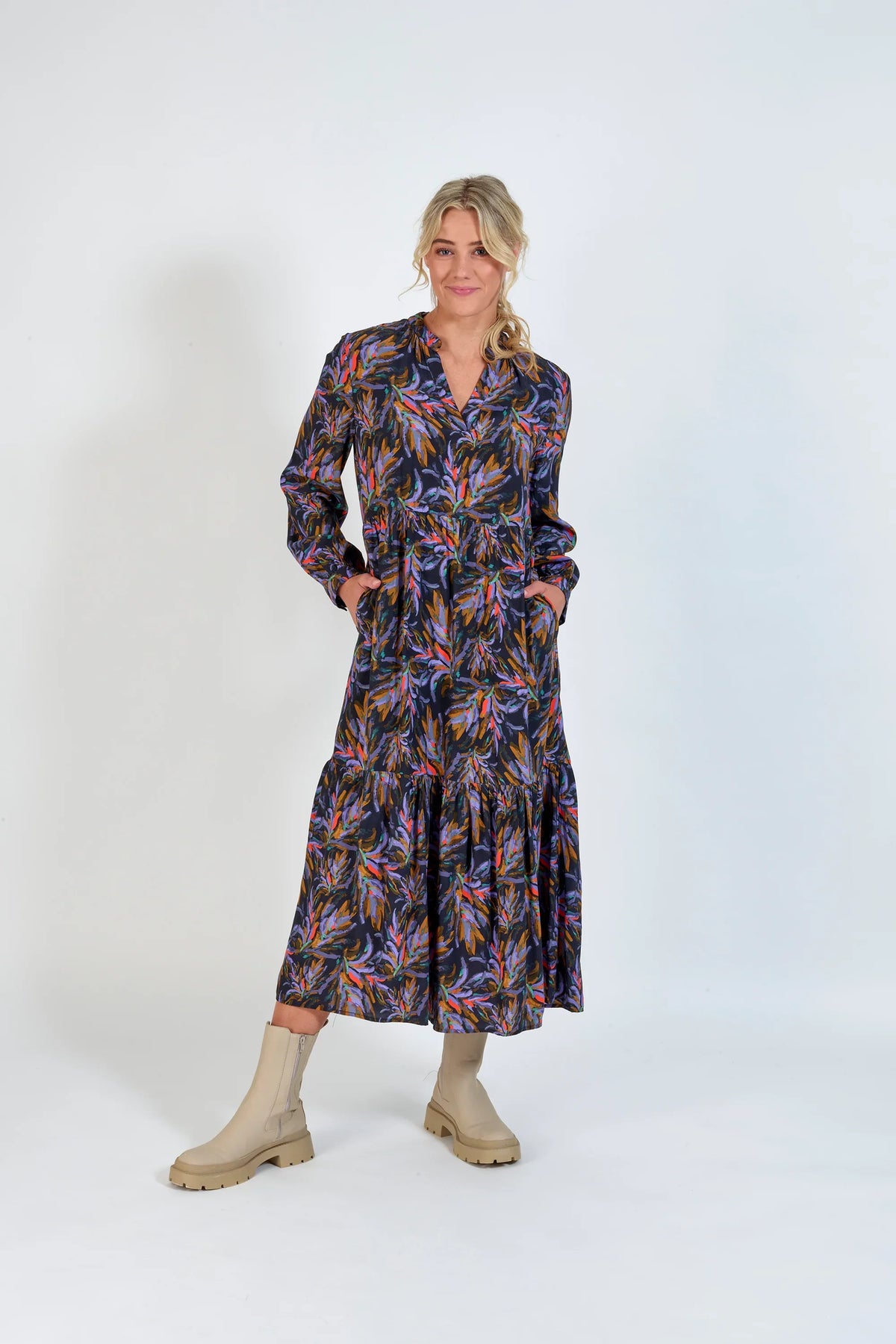 Woman wearing long-sleeve floral print midi dress with cream ankle boots, studio background