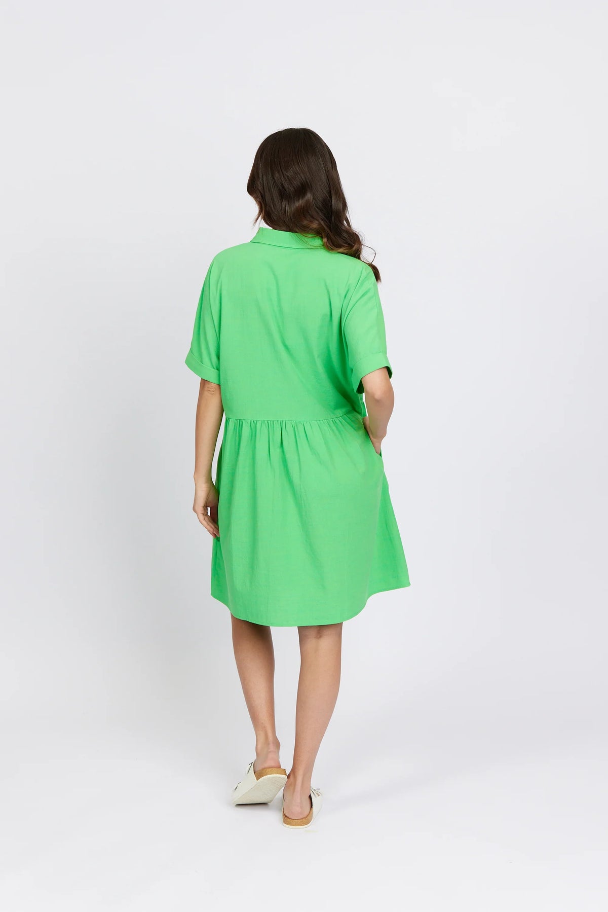 Woman wearing short-sleeve green cocoon dress, back view, casual fashion