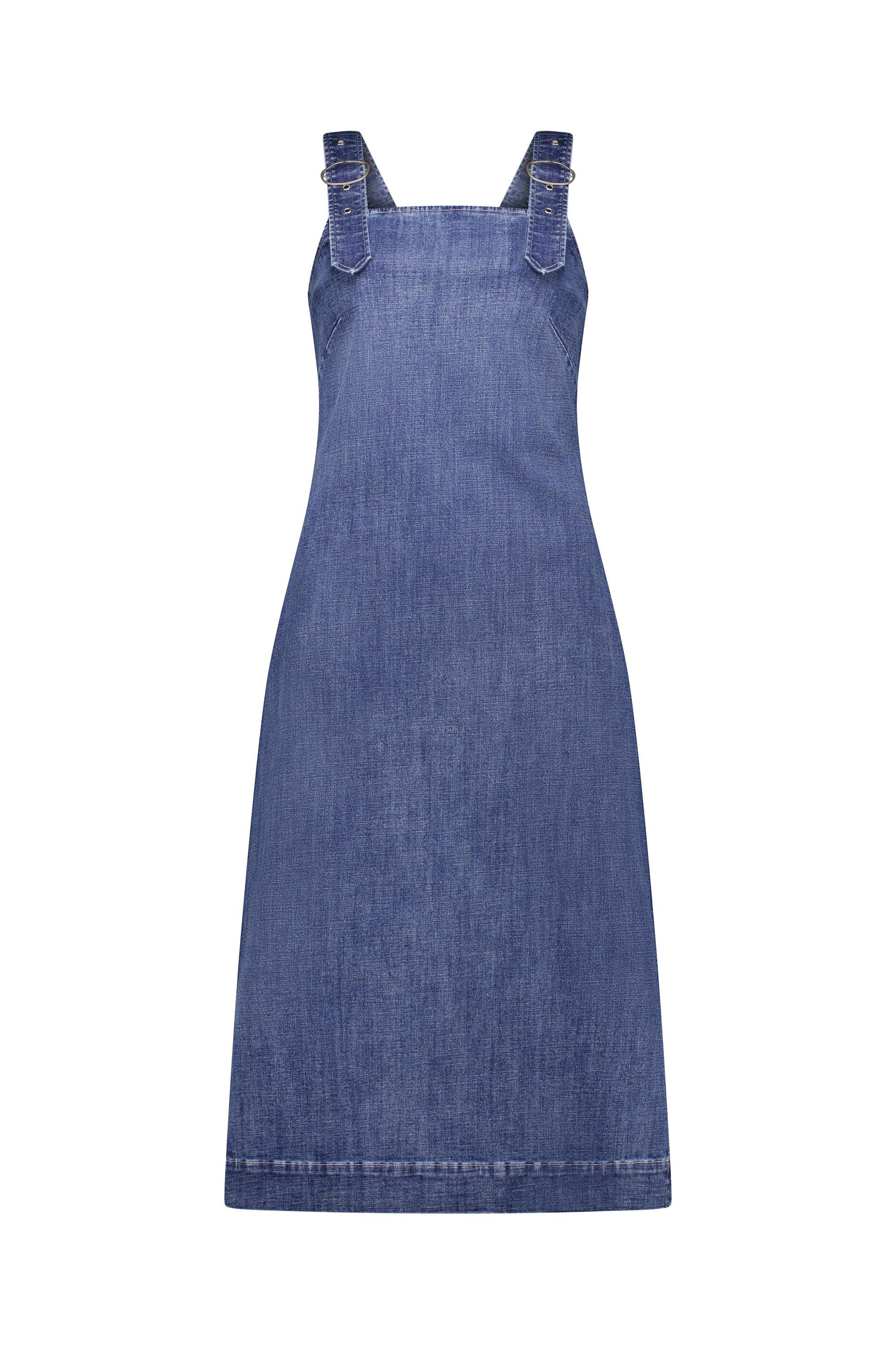 The Academy Dress - Mid Wash by Knewe Label is a sleeveless denim dress with wide pinafore straps, a straight, gently flared fit, and visible seam stitching for a minimalist look. Made from stretch denim.