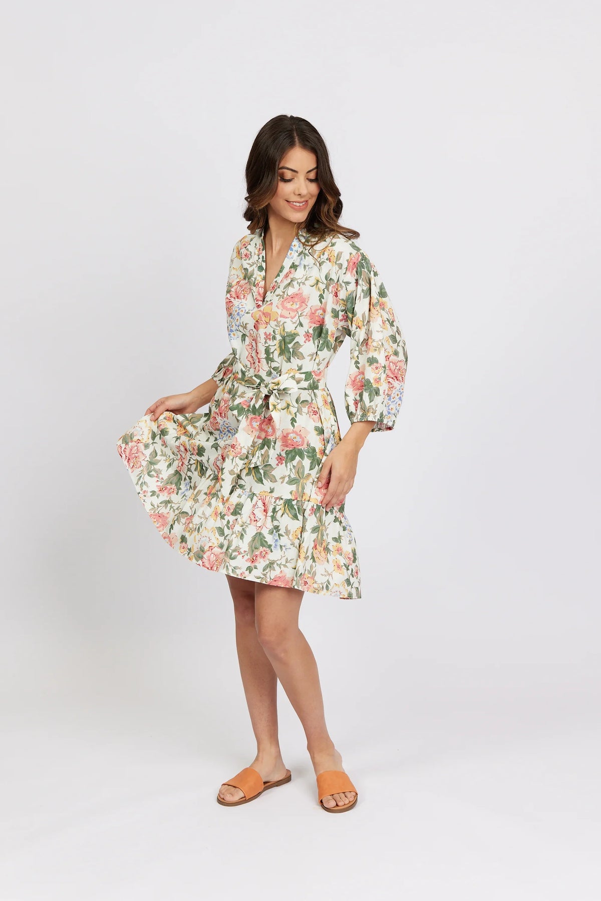 Woman wearing a knee-length floral print dress with long sleeves and a waist tie