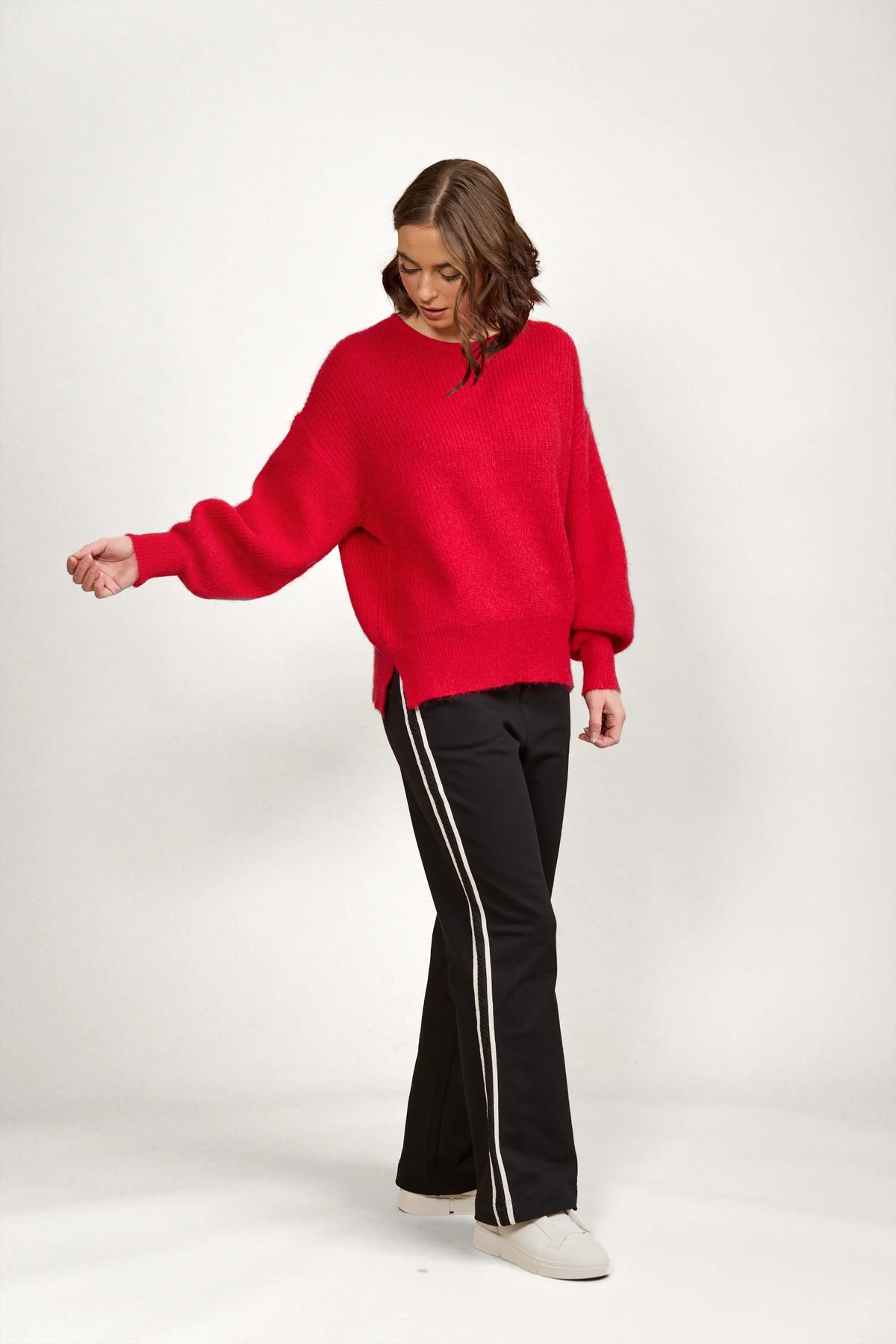 Woman wearing a bright red oversized knit sweater with black pants and white sneakers