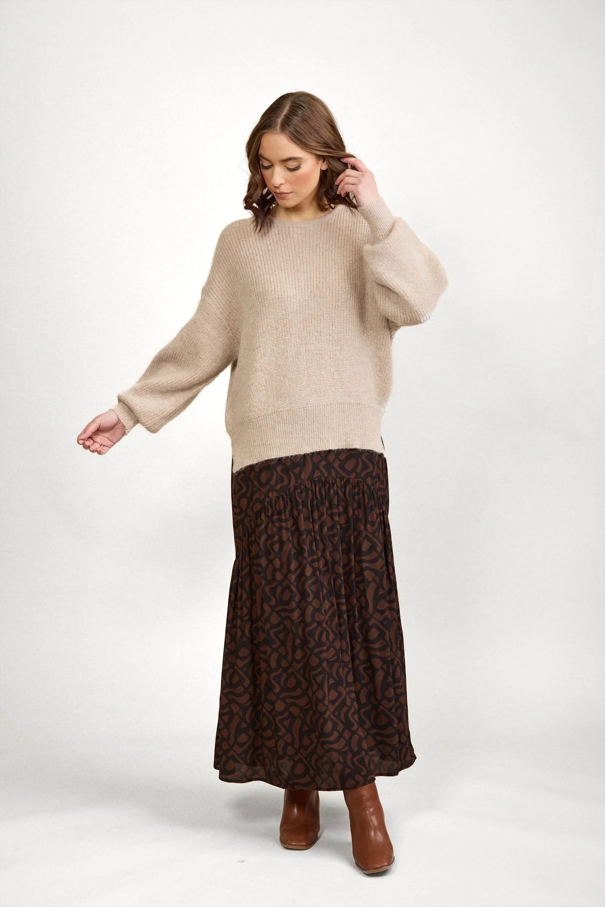 Woman in oatmeal knit sweater and brown patterned maxi skirt with ankle boots