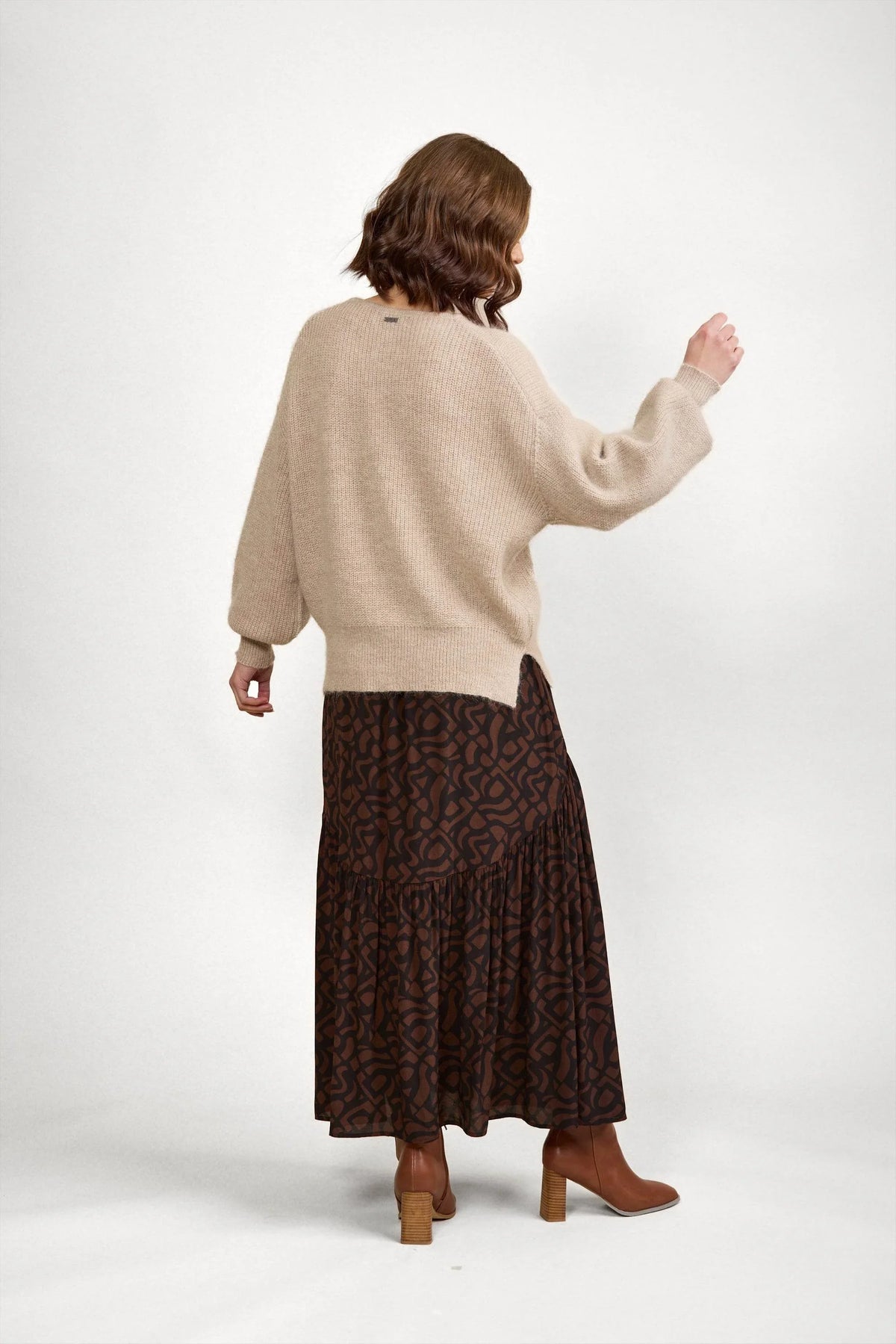 Woman wearing oatmeal knit sweater and brown patterned maxi skirt with heeled boots