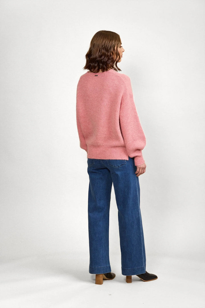 Woman wearing a pink knit sweater and blue wide-leg jeans, viewed from behind