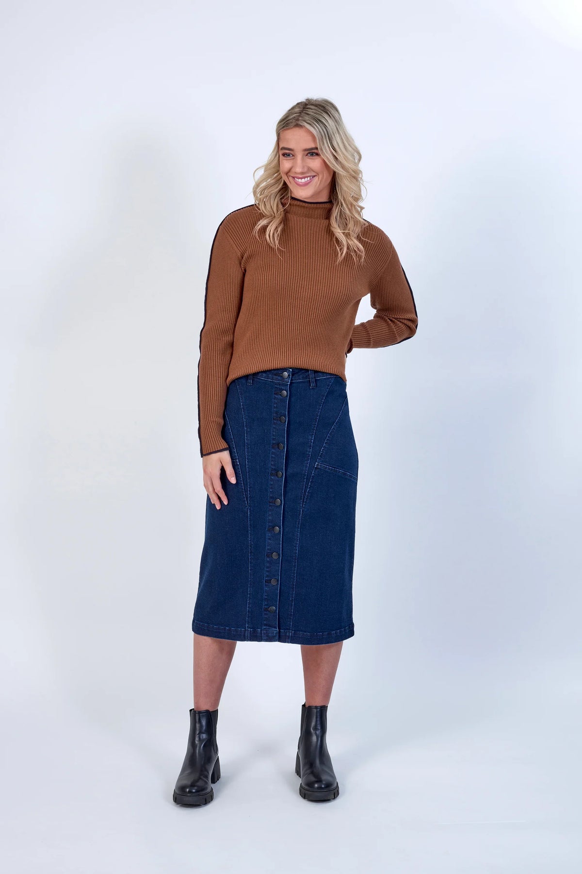 Woman in brown ribbed turtleneck, button-front denim midi skirt, and black boots