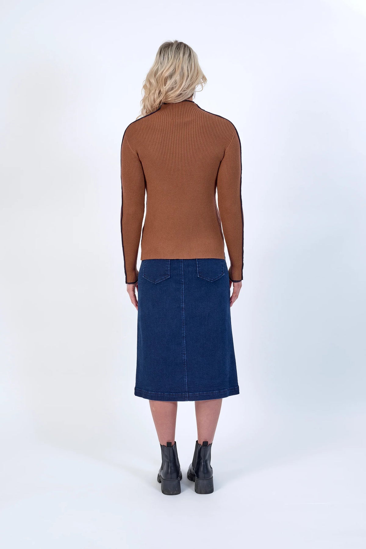 Back view of woman in ribbed brown sweater, denim midi skirt, and black boots — stylish knitwear outfit