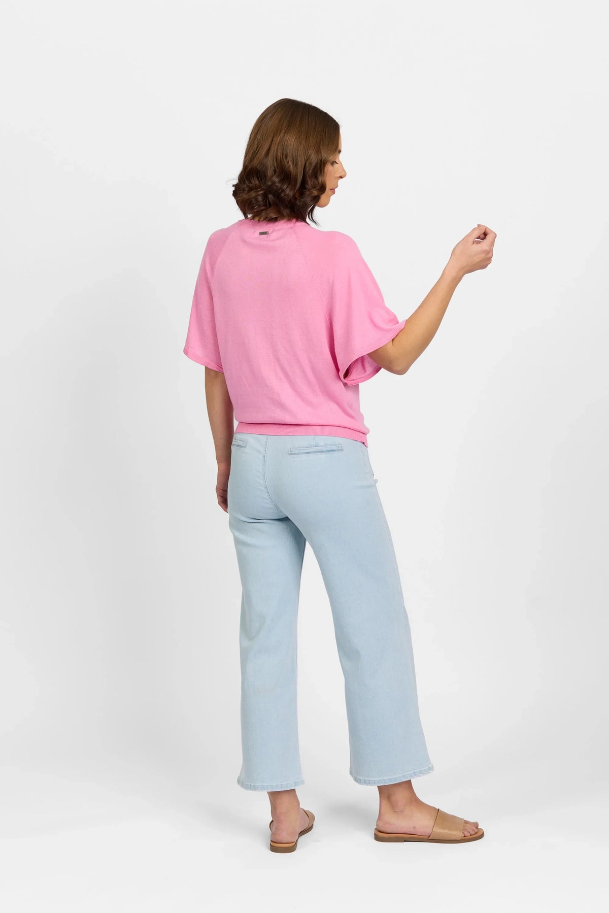 Woman wearing a bubblegum pink knit sweater with light blue straight-leg jeans