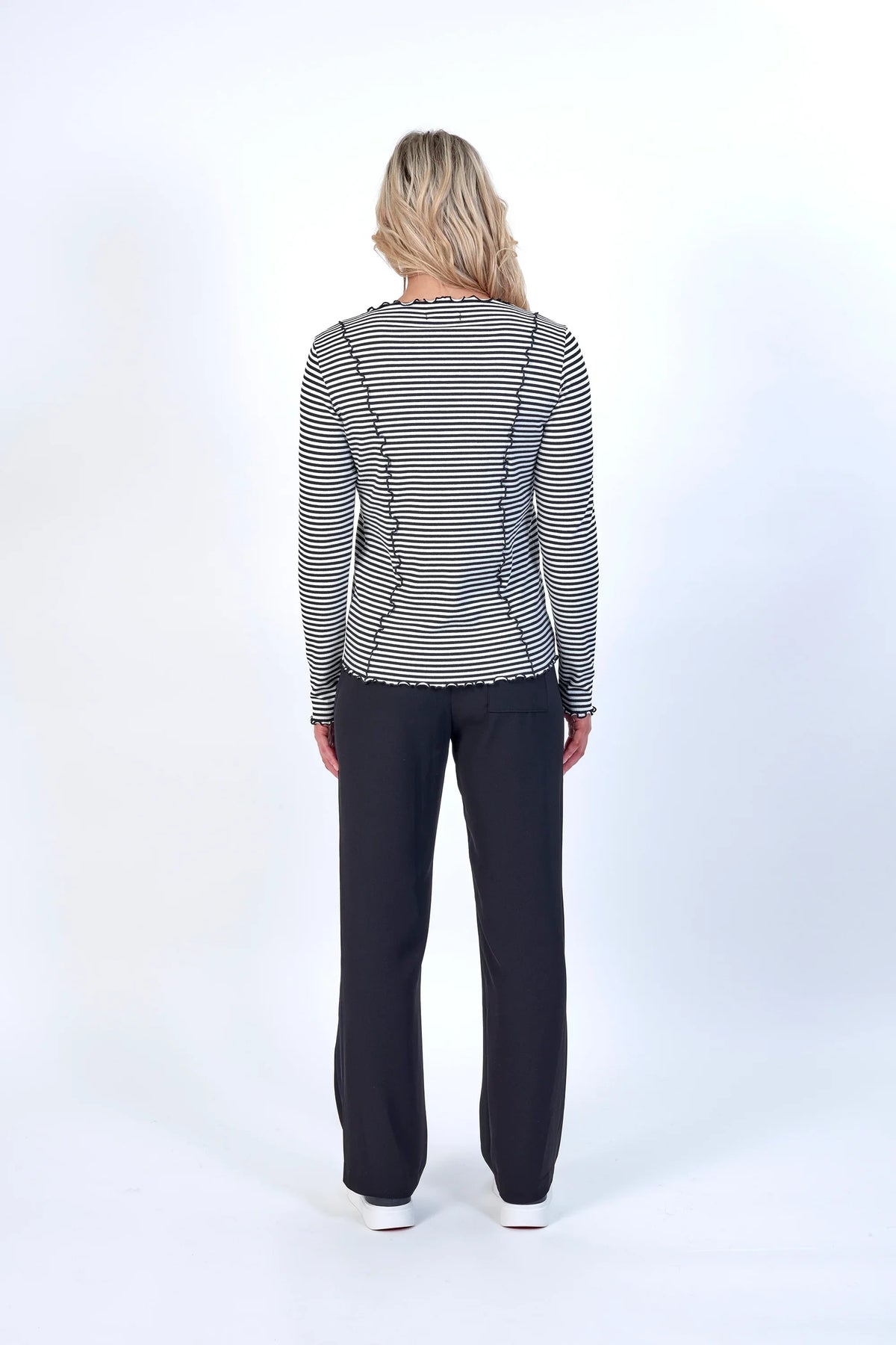 Back view of woman wearing black and white striped long sleeve top and black pants