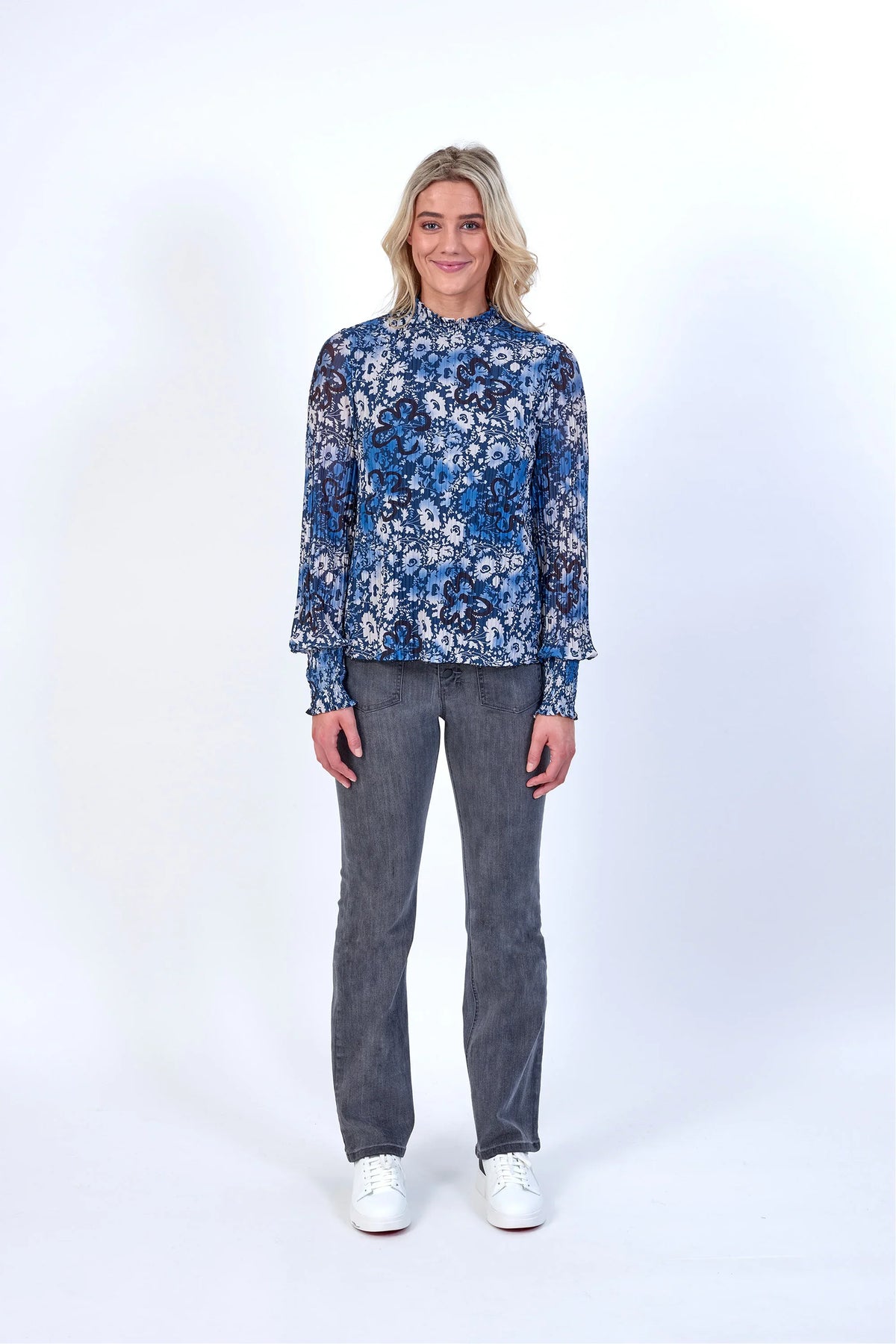 Woman wearing blue floral long sleeve blouse with grey jeans and white sneakers