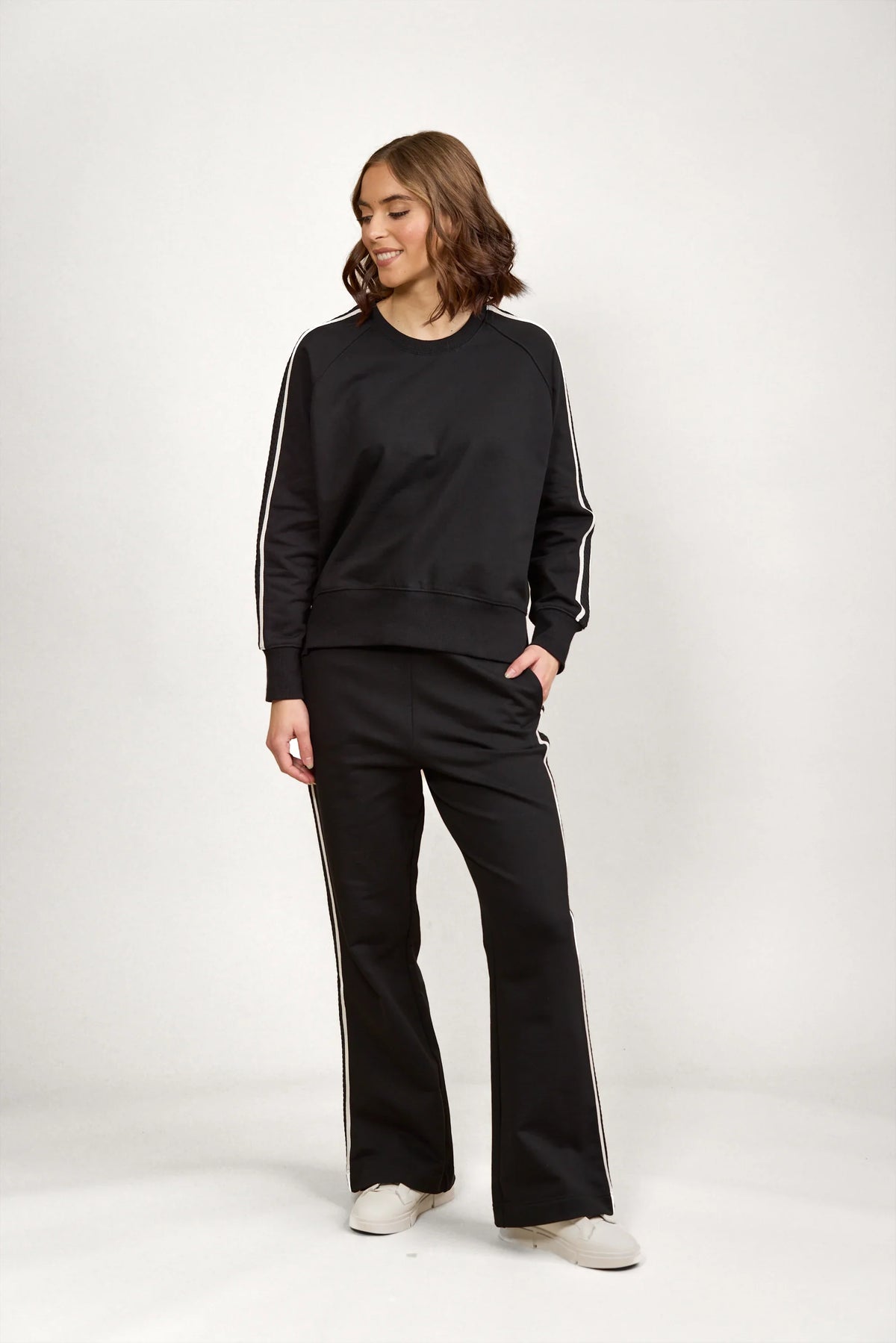 Woman wearing black jumper and pants set with white side stripes, casual fashion outfit