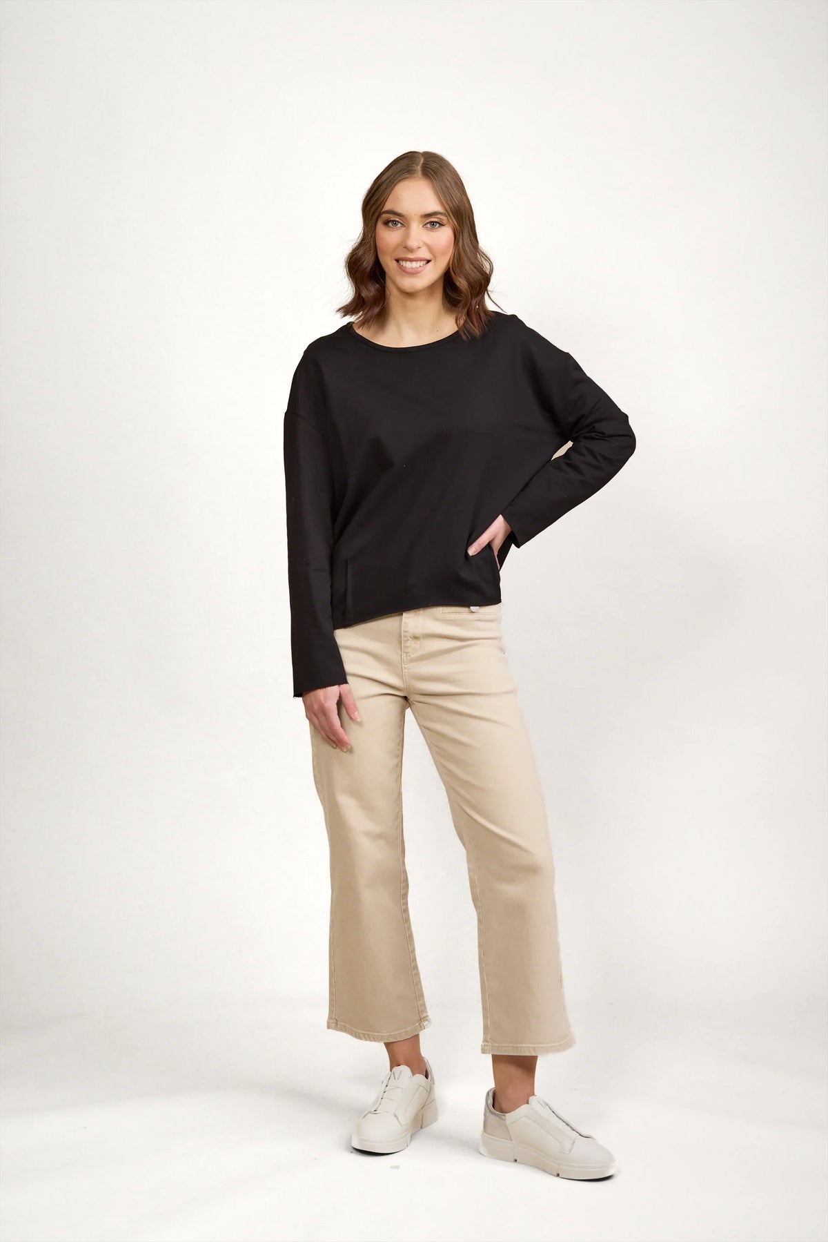 Woman wearing black long sleeve top with beige wide-leg pants and white sneakers