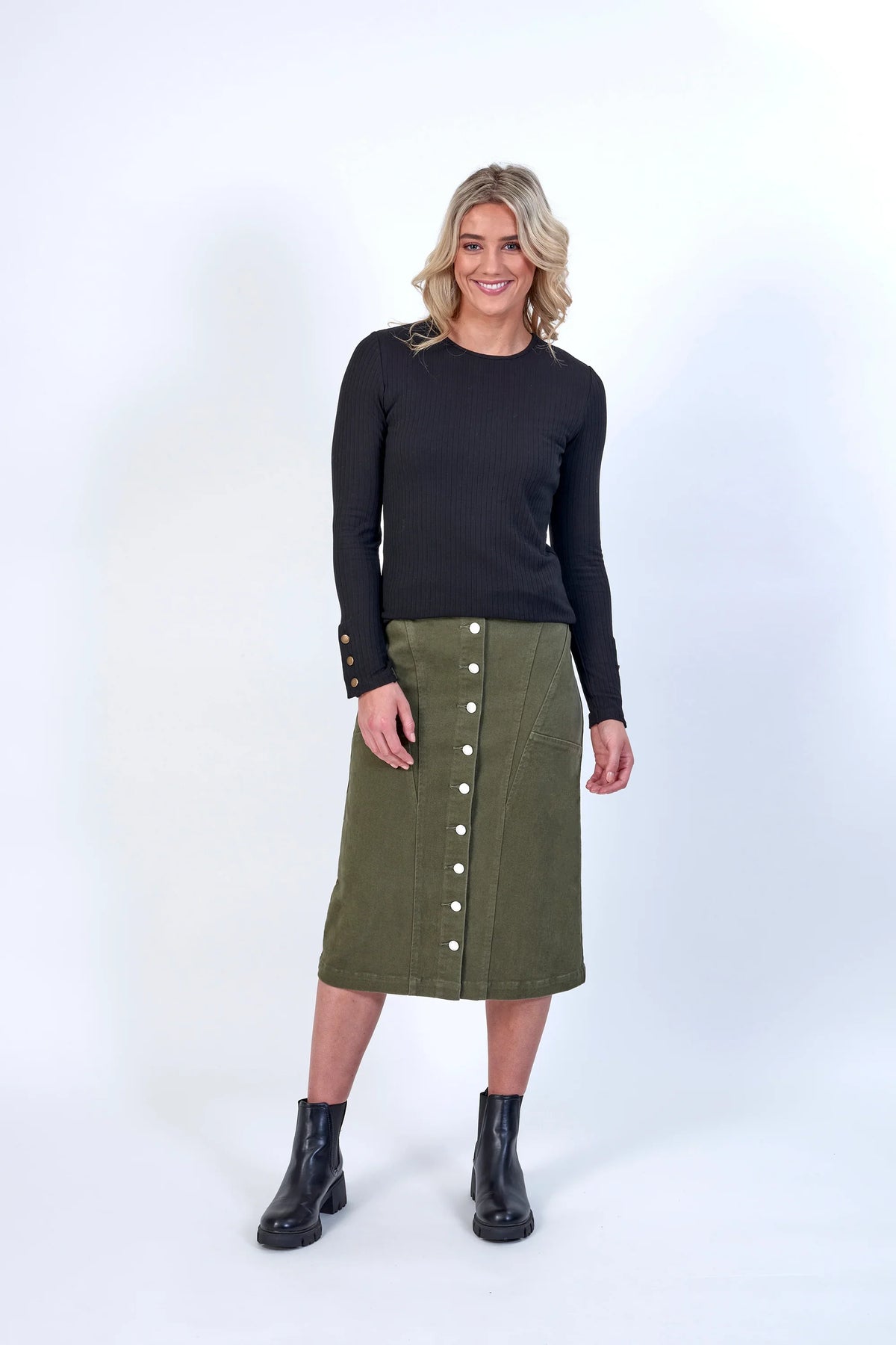Woman wearing a khaki button-front midi skirt, black top, and black ankle boots.