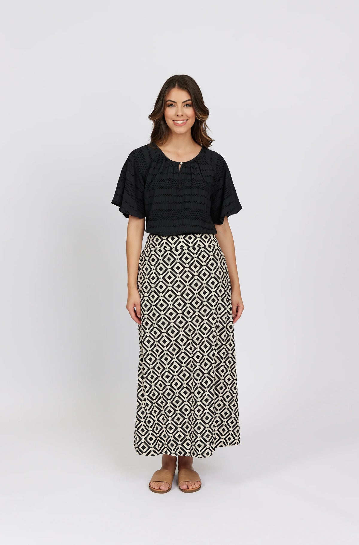 Woman wearing a black short-sleeve blouse and geometric print maxi skirt