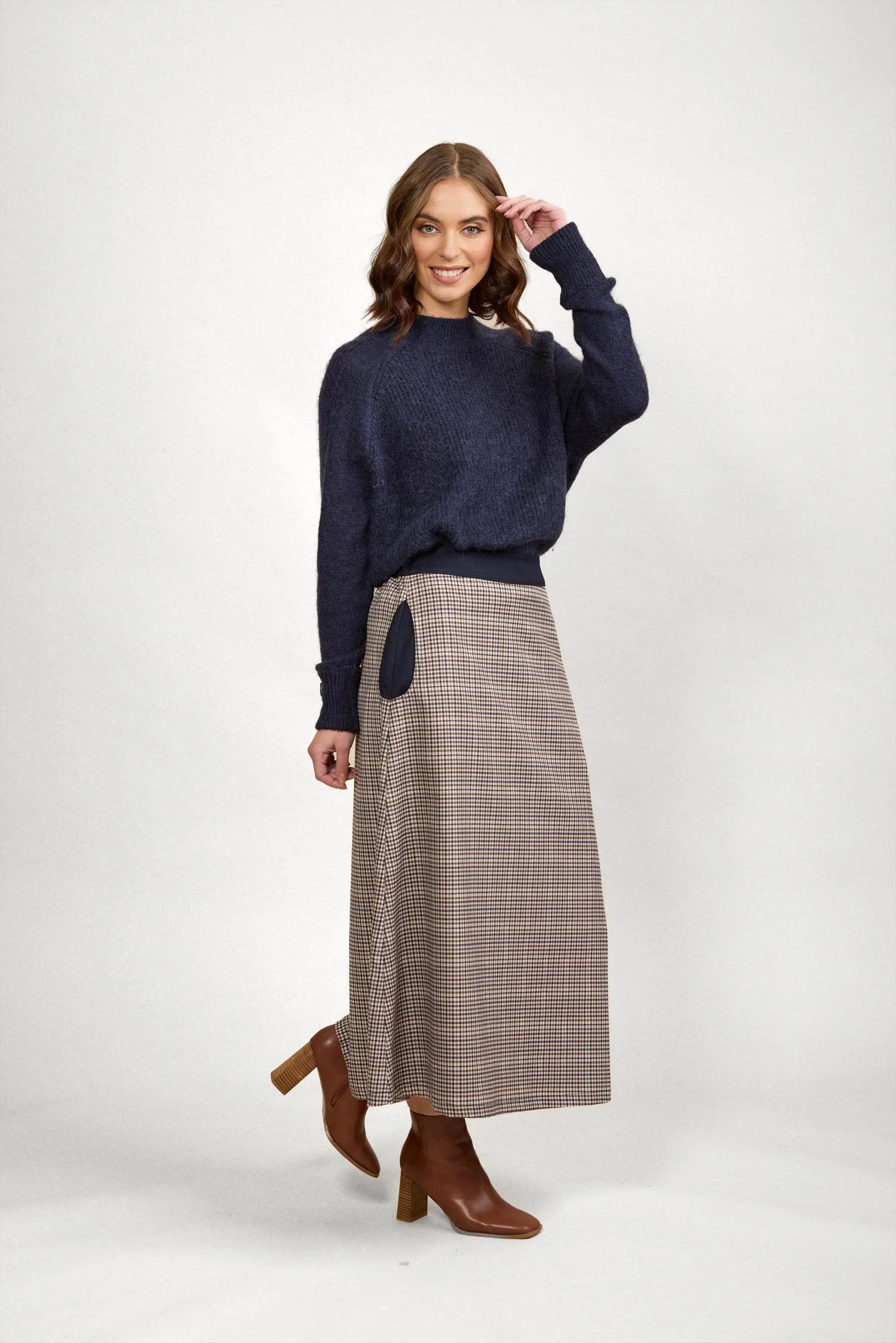 Woman in navy knit sweater and brown check maxi skirt with brown boots