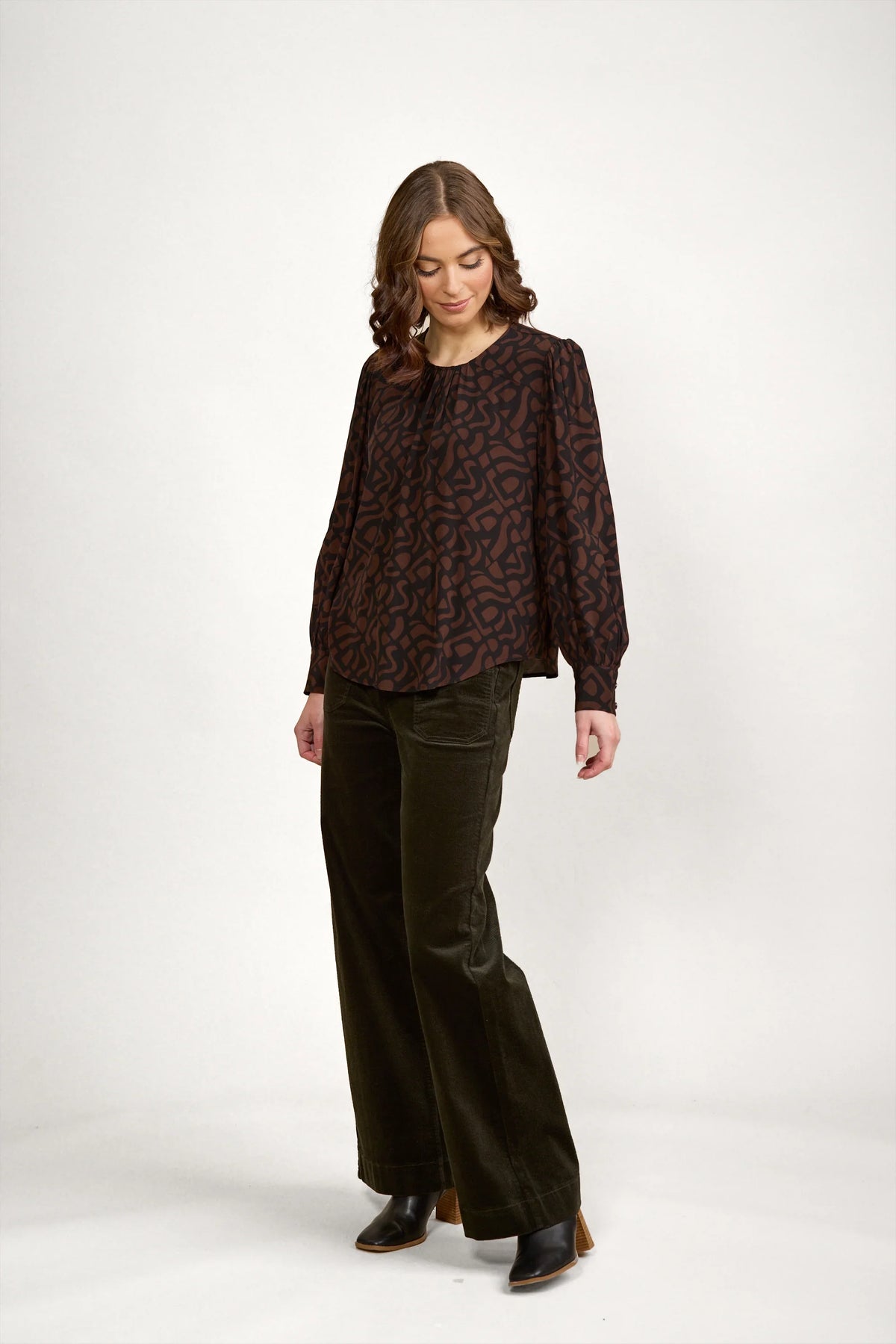 Woman wearing mocha patterned long sleeve blouse with wide leg dark pants and black boots