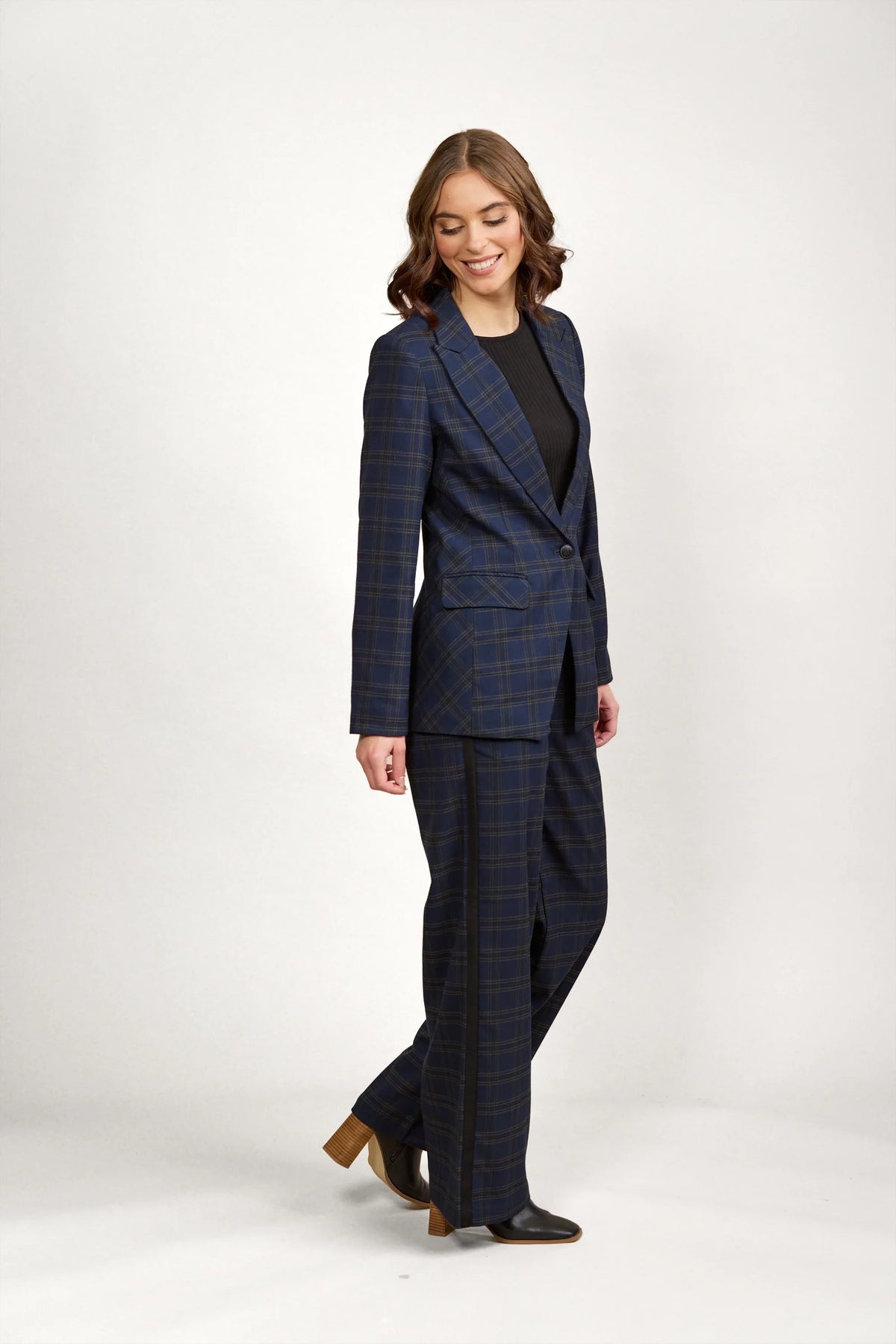 Woman wearing a blue checkered blazer and matching pants, black top and heeled boots
