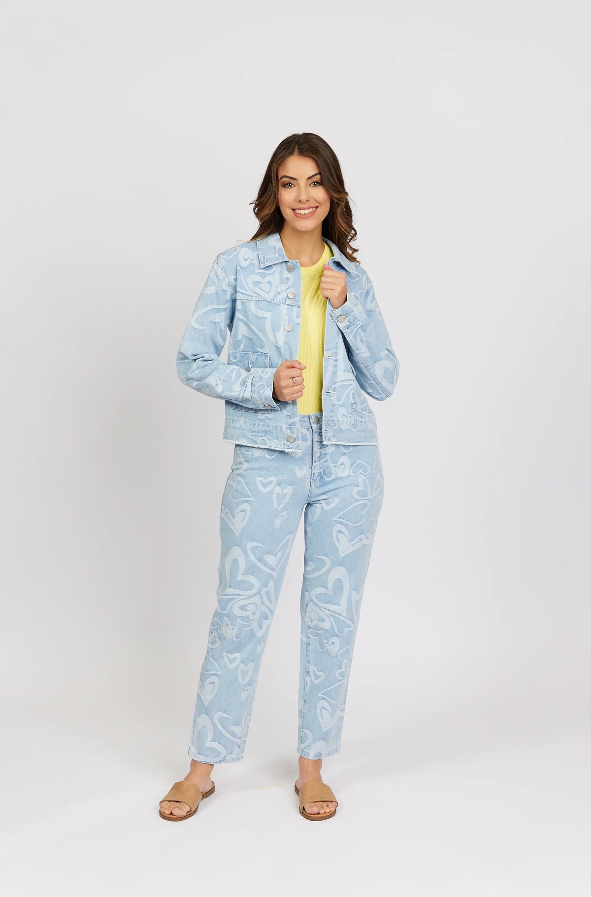 Woman wearing light blue denim jacket and jeans with white heart patterns, yellow top
