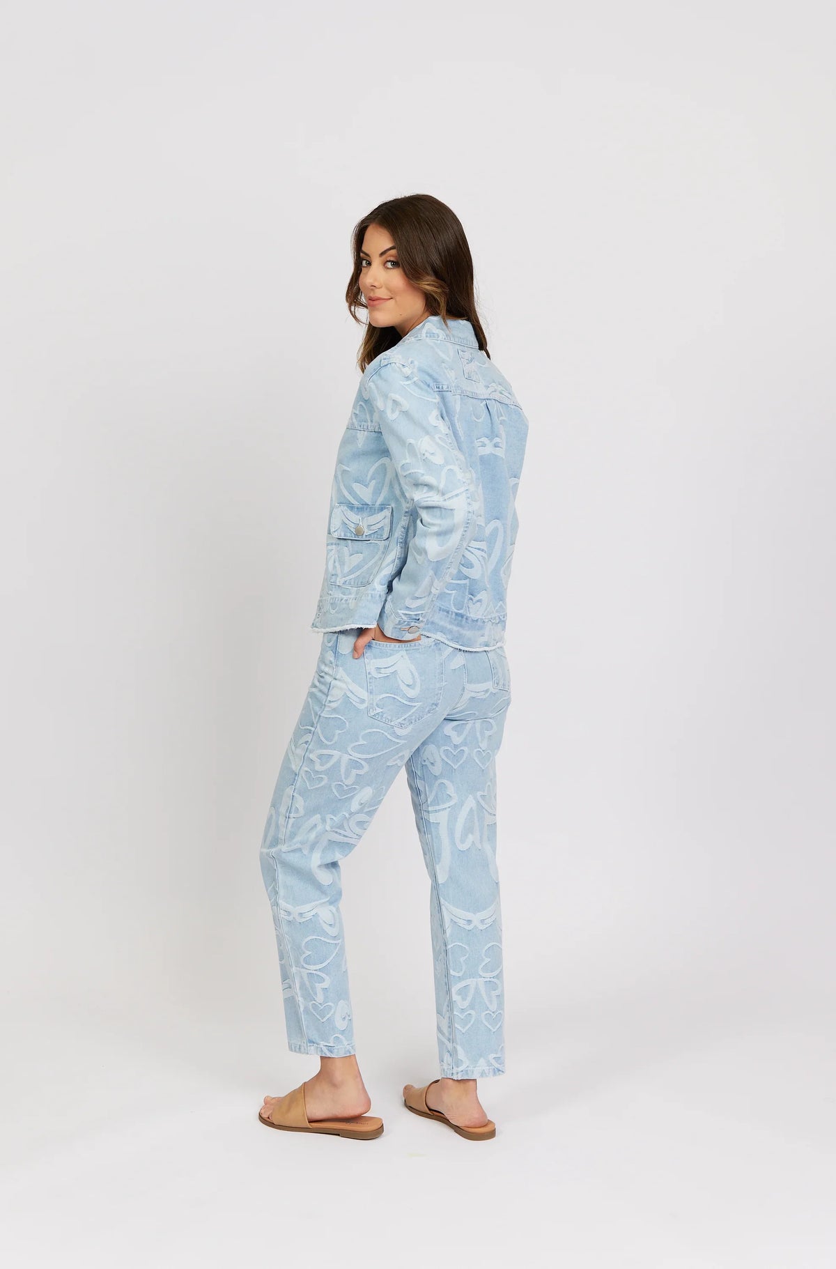 Woman modeling light blue denim jacket and jeans with white heart pattern, casual fashion.