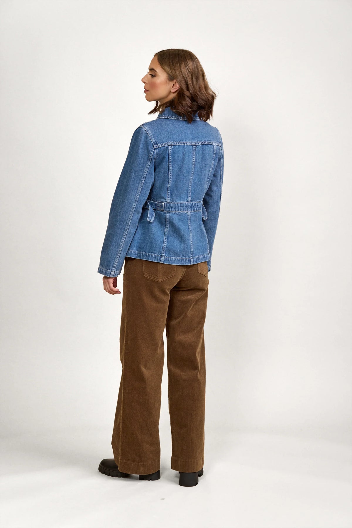 Woman wearing a blue denim jacket and brown wide-leg pants, shown from the back