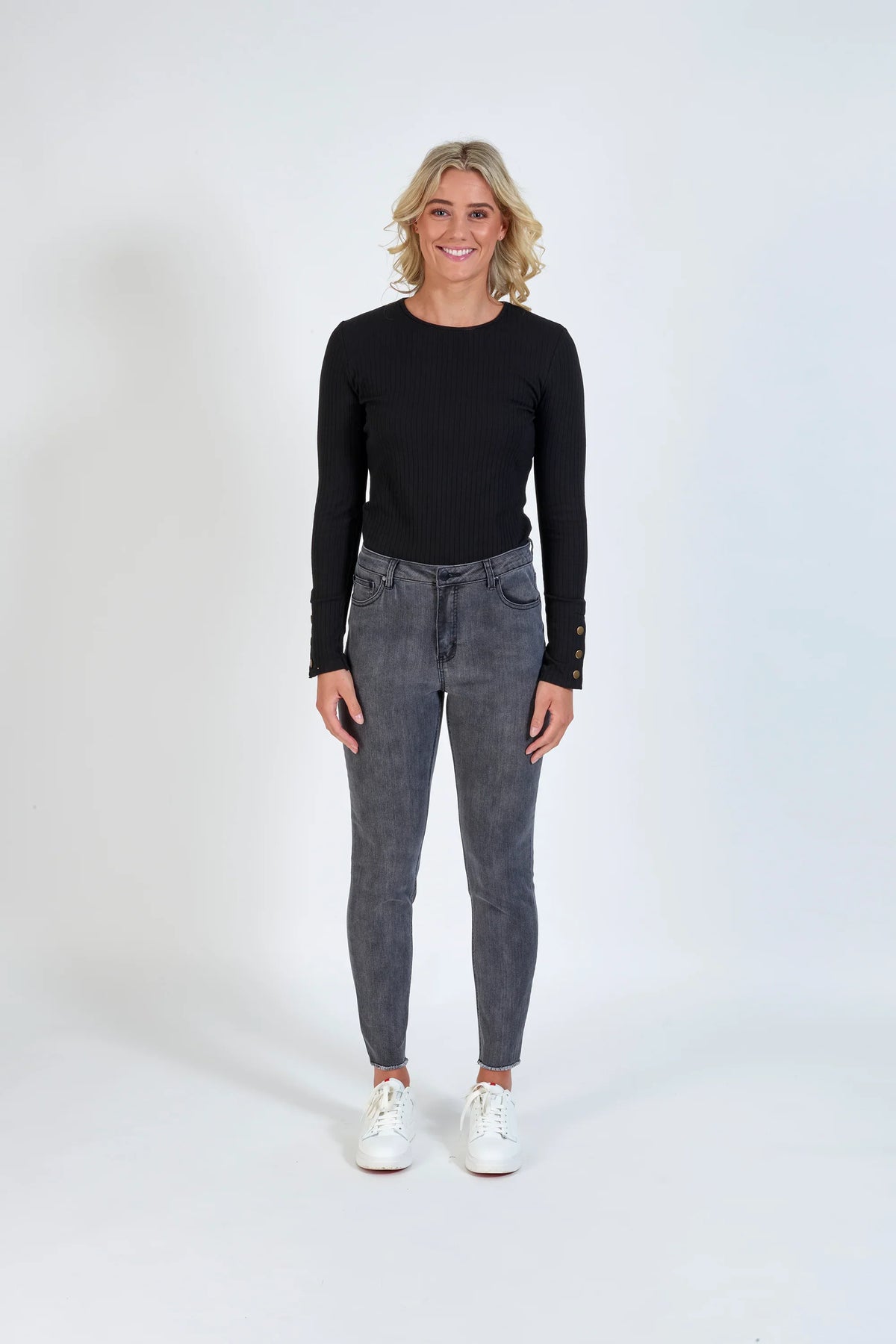 Woman wearing space grey skinny jeans, black long sleeve top, and white sneakers