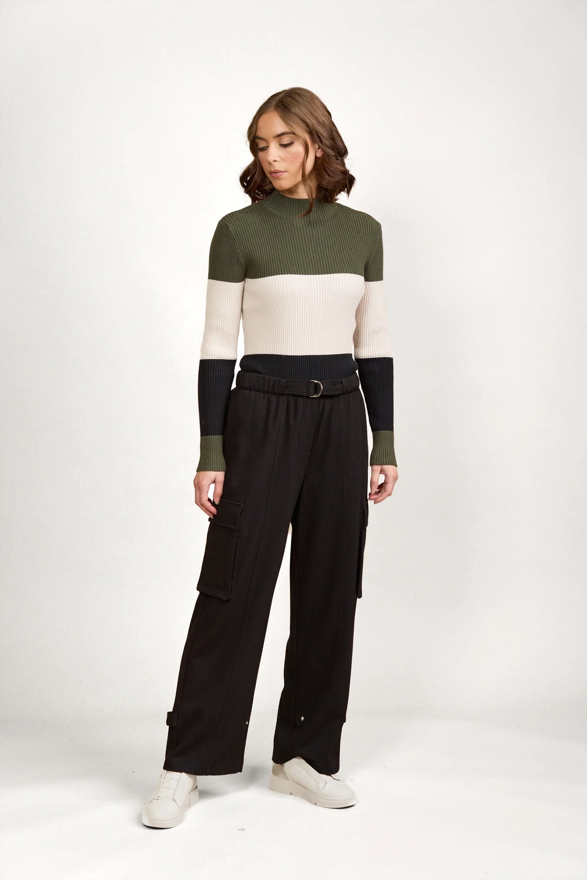 Woman wearing high-waisted black cargo pants and colorblock knit sweater in studio