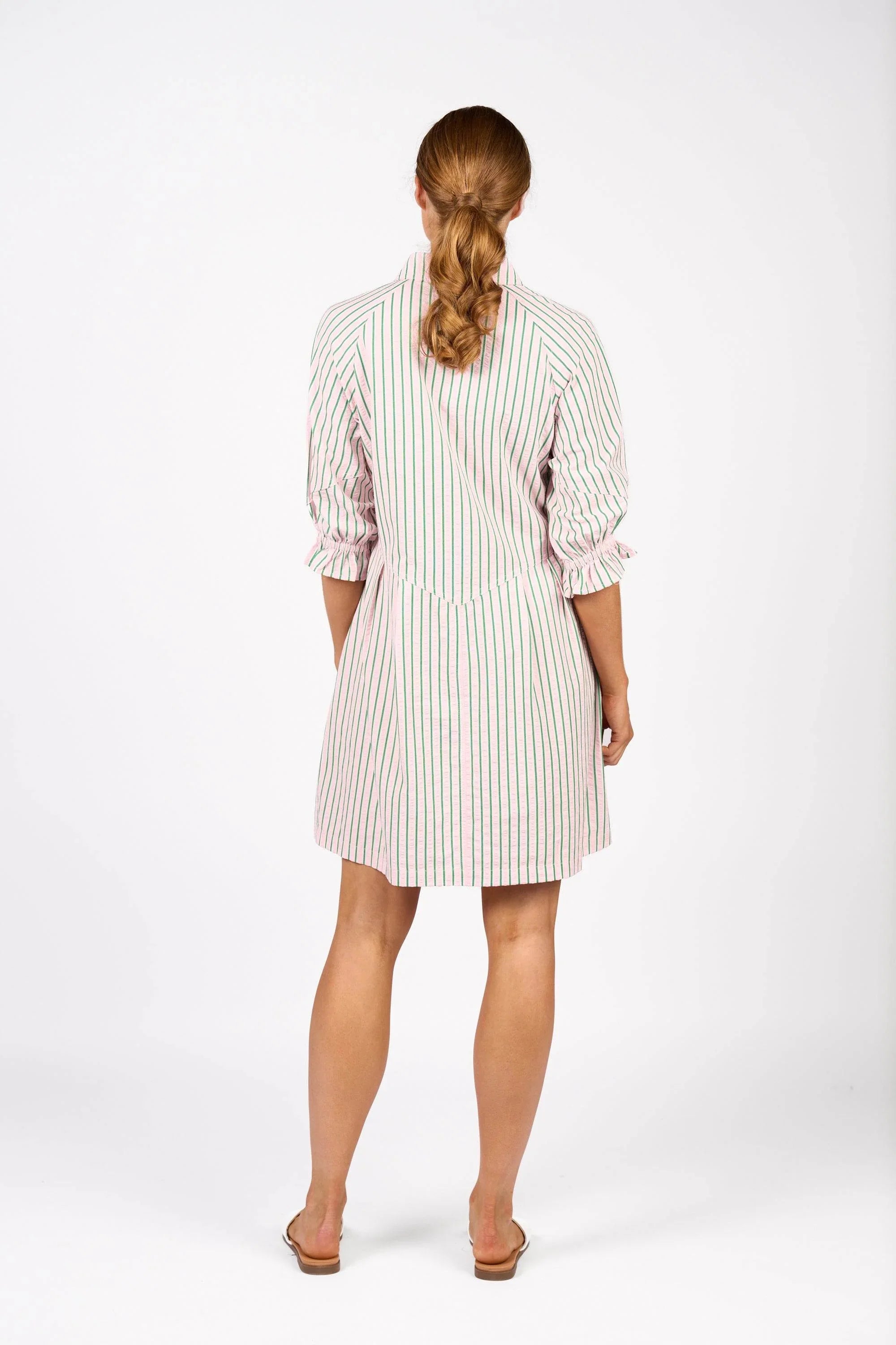 Back view of woman in long sleeve mini dress with pink and green vertical stripes